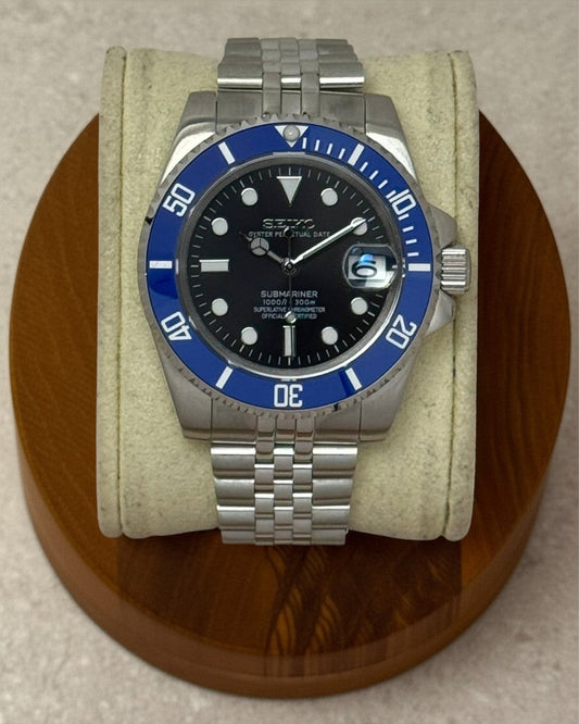 PB TimePiece Submariner Cookiemonster watch with a black dial, blue rotating bezel, and stainless steel jubilee band.