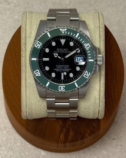 PB TimePiece Submariner Starbucks watch with a black dial, green rotating bezel, and stainless steel oyster bracelet.