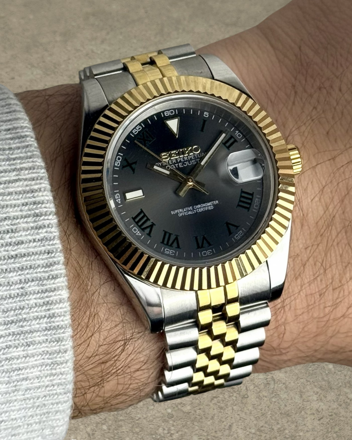 PB TimePiece Classic Date watch with two-tone gold fluted bezel, jubilee bracelet, and dark Wimbledon dial on wrist.