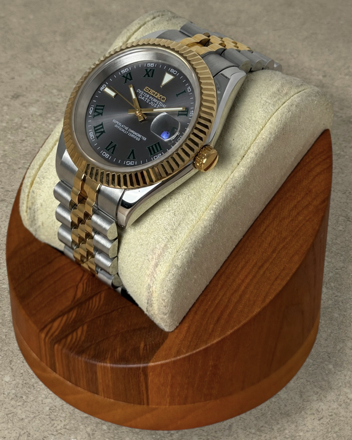PB TimePiece two-tone gold watch with a grey Wimbledon dial, fluted bezel, and jubilee bracelet on a wooden stand.