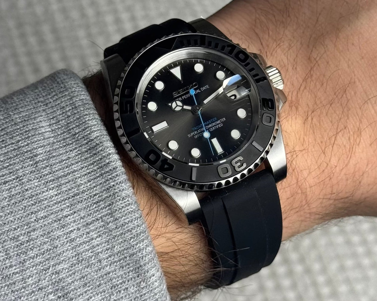 PB TimePiece Yachtmaster Blue Ember watch with a gray dial, matte black bezel, and black rubber strap on a wrist.