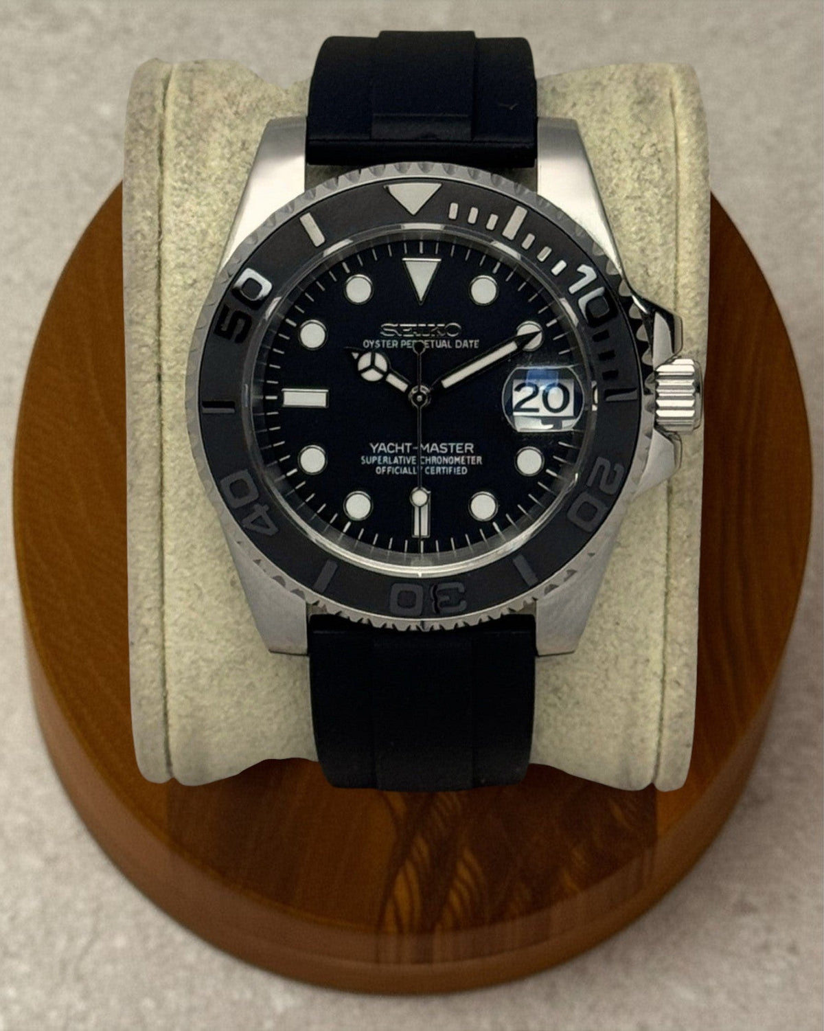 PB TimePiece Yachtmaster watch with a matte black dial, rotating bezel, and black rubber strap on a wooden stand.