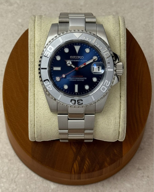 PB TimePiece Yachtmaster watch with navy blue dial, stainless steel case, oyster bracelet, and matte gray bezel.