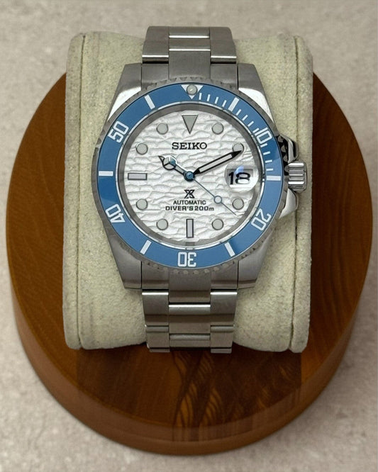 PB TimePiece Yachtmaster watch with a sky blue bezel, white wave-textured dial, and stainless steel oyster bracelet.