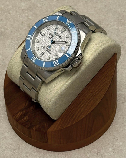 PB TimePiece Yachtmaster watch with sky blue bezel, white wave-textured dial, and stainless steel oyster bracelet.